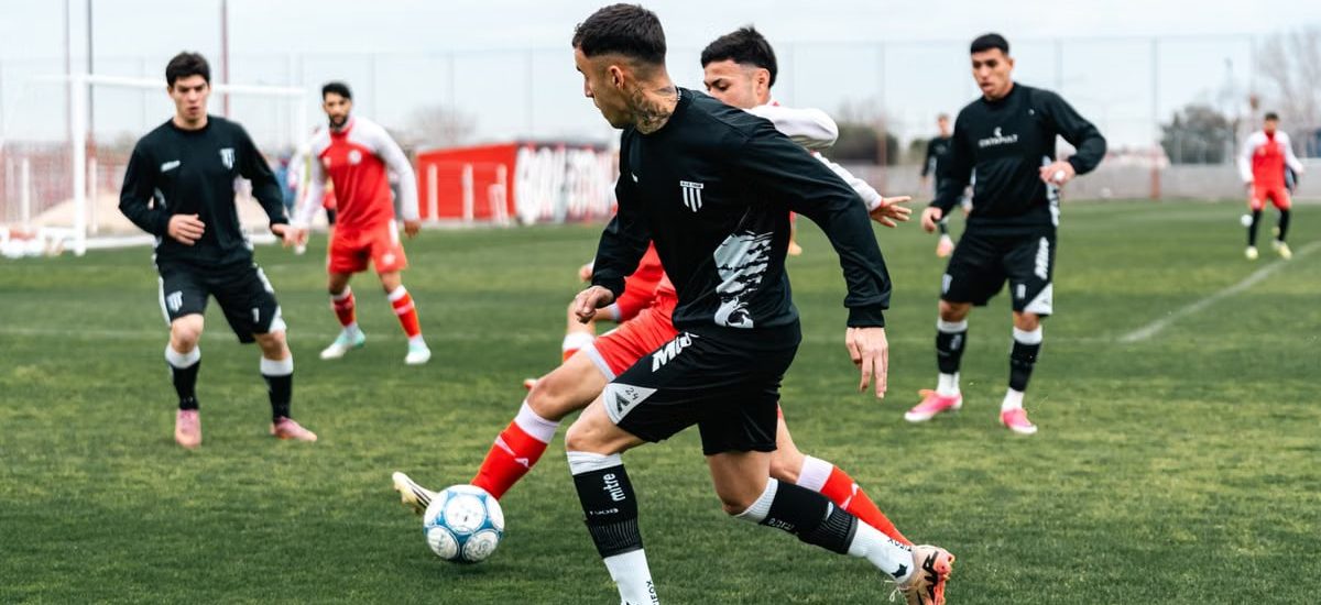 Dynamic soccer match with players in black and red jerseys engaged in a game on a green field.