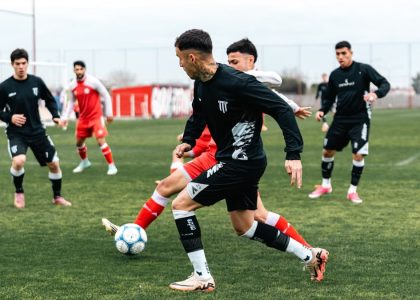 Dynamic soccer match with players in black and red jerseys engaged in a game on a green field.
