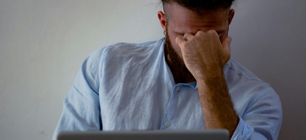 man in blue dress shirt holding silver macbook
