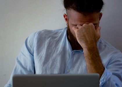 man in blue dress shirt holding silver macbook